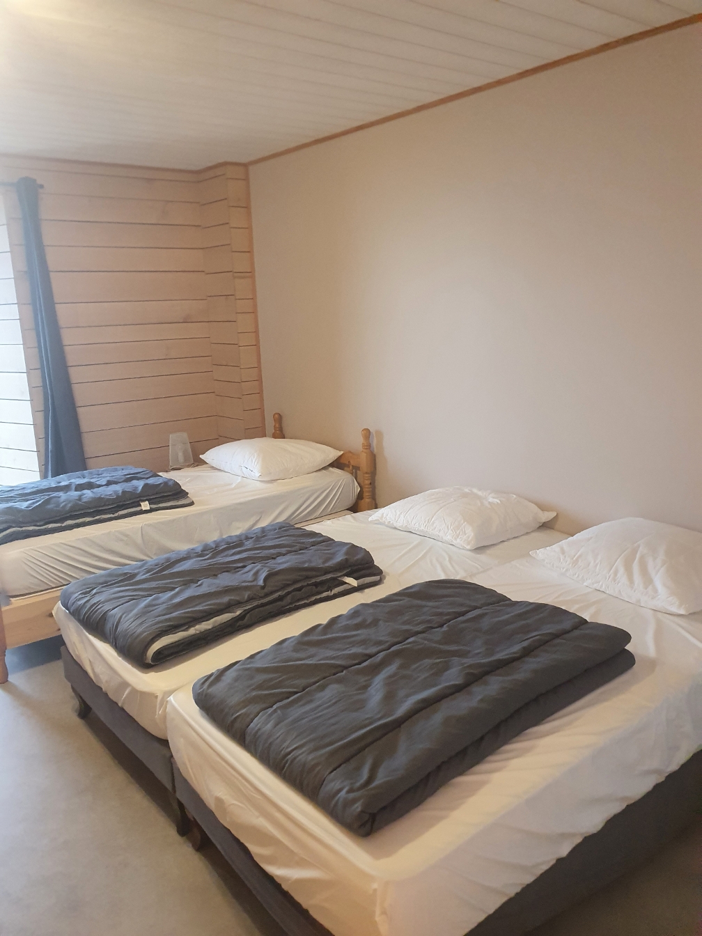 Chambre du Grand Planchat avec trois lits simples et lambris clair