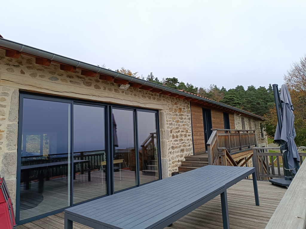 Terrasse en bois longeant la façade en pierre du Grand Planchat