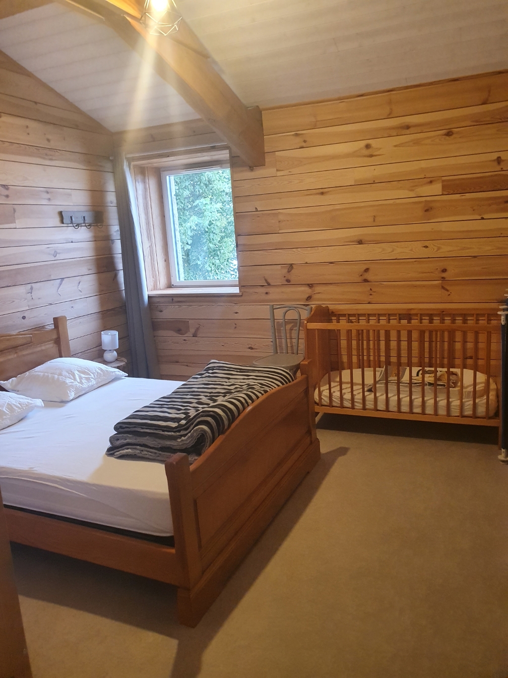 Chambre du Grand Planchat avec lit double, boiseries claires et lit bébé