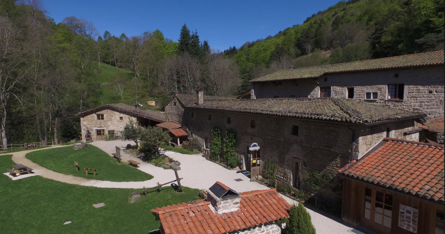 Moulin des Massons et ses bâtiments en pierre dans une vallée boisée du Forez