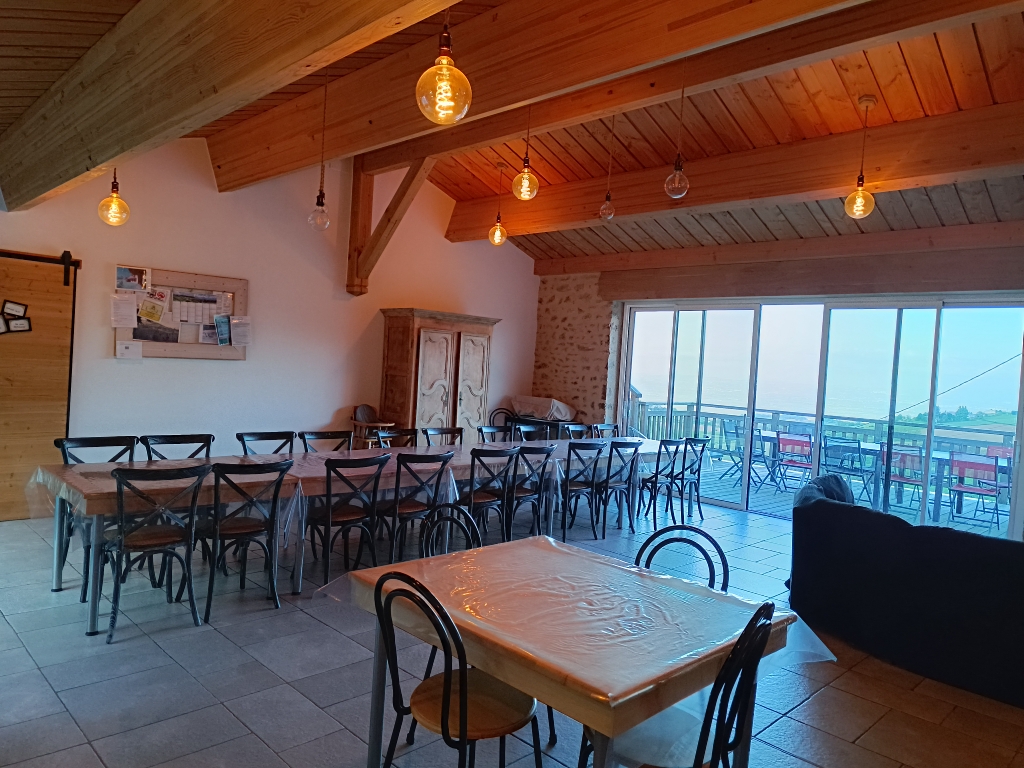Grande salle du Grand Planchat ouverte par ses baies vitrées sur la terrasse