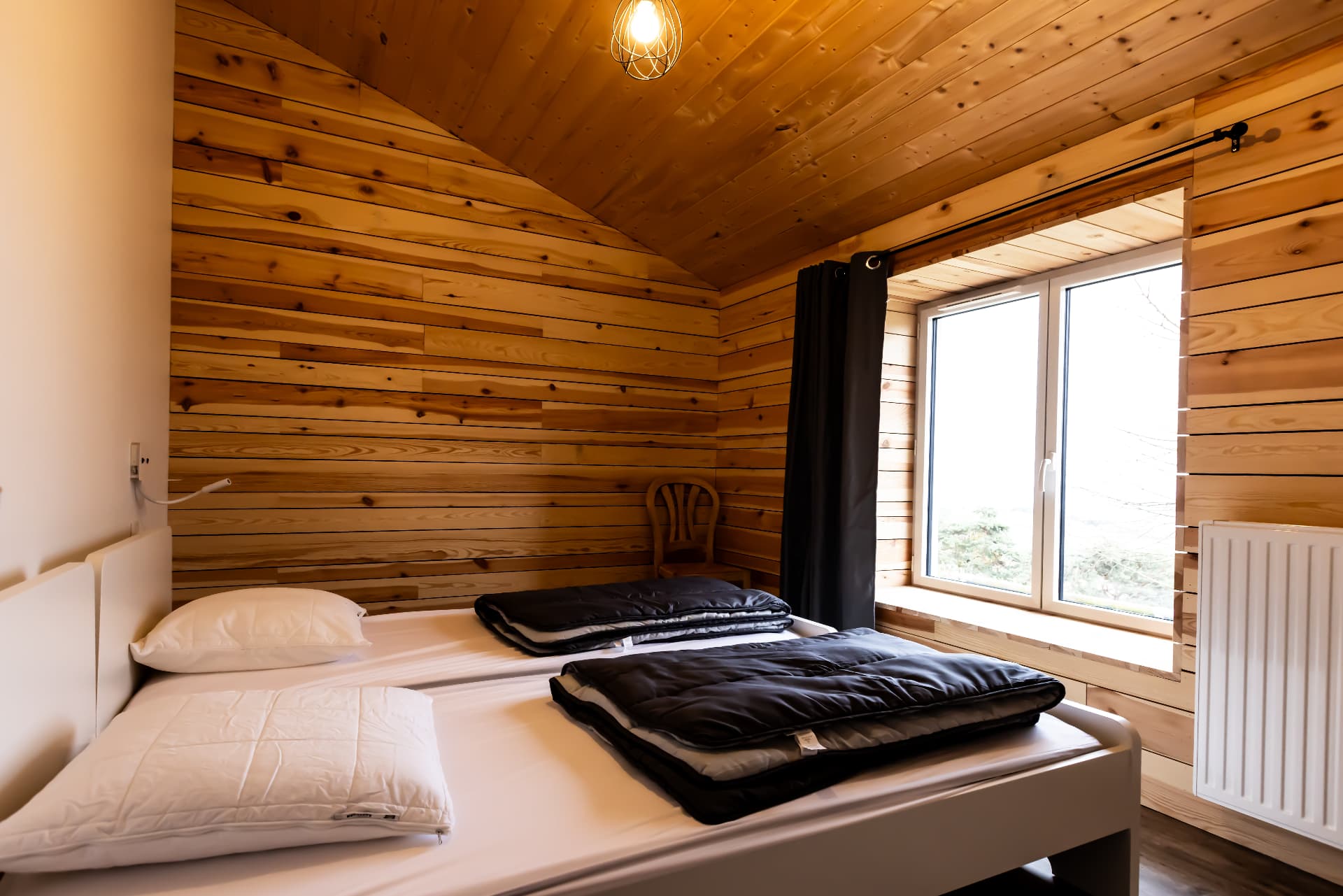 Chambre du Petit Planchat avec deux lits simples et vue sur les arbres